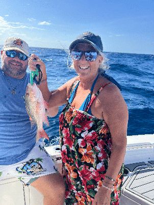 A couple showing off their catch aboard a Salty Buddha charter