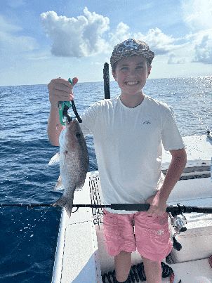 Young angler holding a fish under blue Florida Keys skies